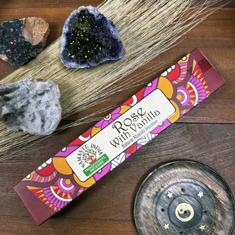 Smilkalai Rose with Vanilla pakuotėje, natūralūs masala aromatai, spalvinga dėžutė parodyta ant medinio fono su kristalu ir laikikliu.