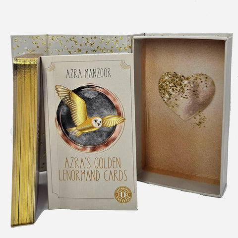 Lenormand kortos Azra Manzoor su auksuotais kraštais, priešais atidarytą dėžutę su blizgančia širdies detalėmis