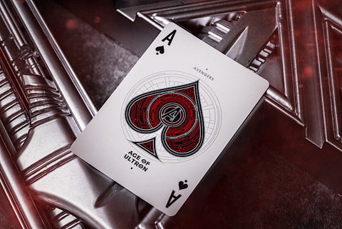 kolekcinė korta „Ace of Spades“ su raudonu Ultron mechanikos piešiniu ant baltos kortelės, uždėta ant metalinio Avengers ženklo