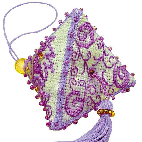 Kvapų pagalvėlė su violetine siuvinėjimo spiralėmis, smulkiais rausvais karoliukais ir auksinėmis akutėmis bei ilgu šviesiai violetiniu kutu