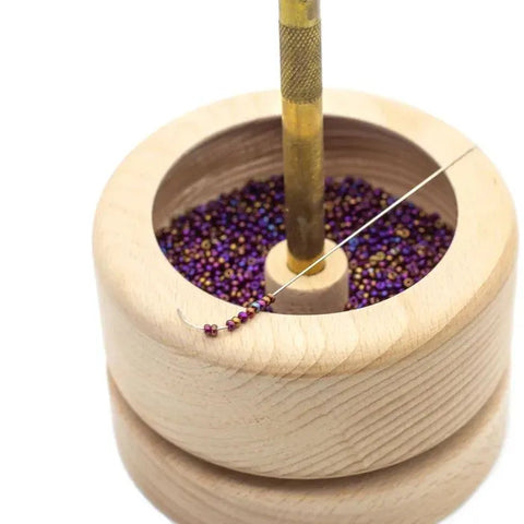 Karoliukų vėrimo įrankis medinis indelis su violetiniais metalizuotais smulkiais karoliukais ir adata vėrimui