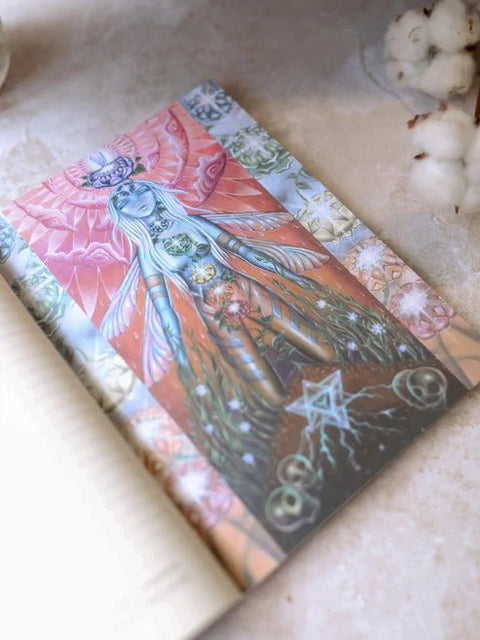 Tarot korta ant užrašų knygos atvarto, koralinė ir žalsva iliustracija su čakromis, kampinis artimas planas, medvilnės dekoracija
