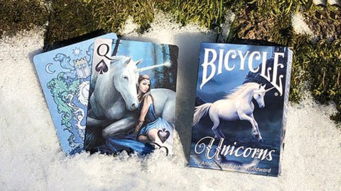 Bicycle Unicorns kortos, mėlyna dėžutė ir dvi atverstos kortos su vienaragiu ir Karaliene ♠ ant sniego