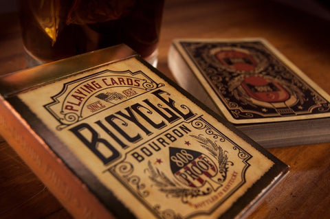 Bicycle žaidimo kortos Bourbon, artimas dėžutės kampo kadras su sendintu smėlio atspalviu ir retro ornamentais