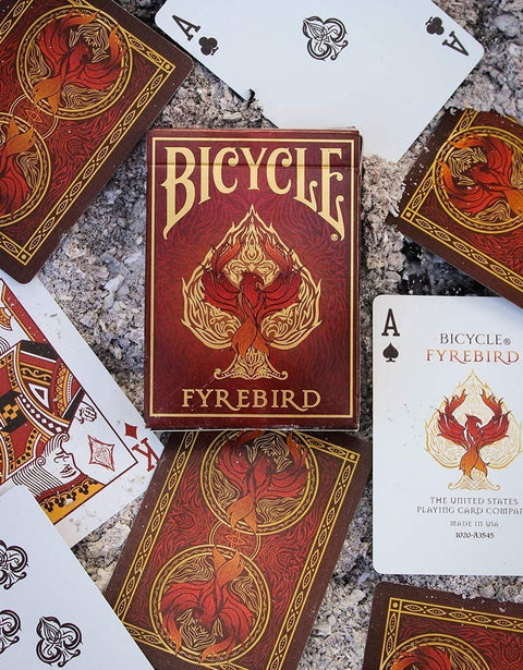 Bicycle Fyrebird kortos raudonai auksiniu dizainu, centrinė dėžutė ir išdėstyti kortų paviršiai matomi iš viršaus
