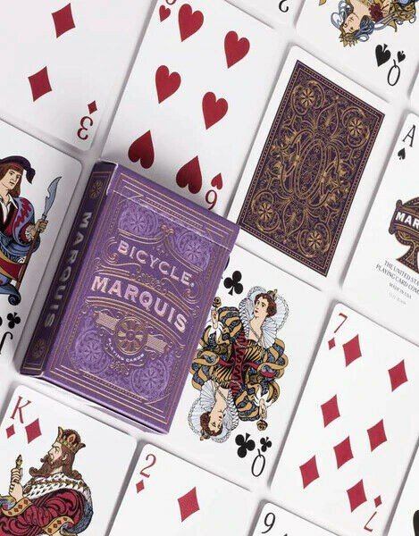 Bicycle Marquis kortų kaladė su violetine dekoratyvia dėžute ir aukso raštais, išdėstyta tarp išskleistų kortų