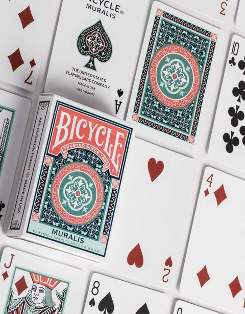 Bicycle Muralis žaidimo kortos su žalia‑koraline ornamentine nugarėle ir dėže, matoma kelių kortų priekis ir galas