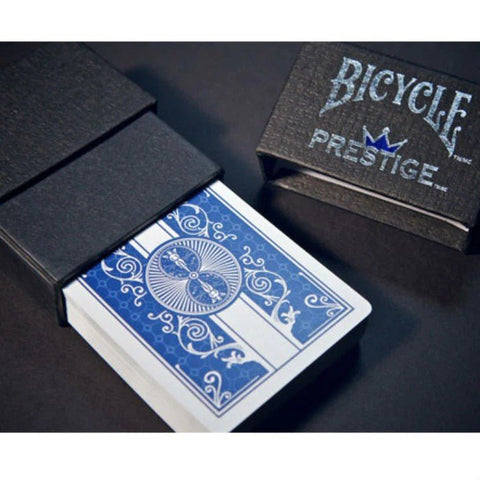 Bicycle Prestige mėlynos žaidimo kortos su ornamentine nugarėle ir juodu magnetiniu dėklu, matomos iš šono