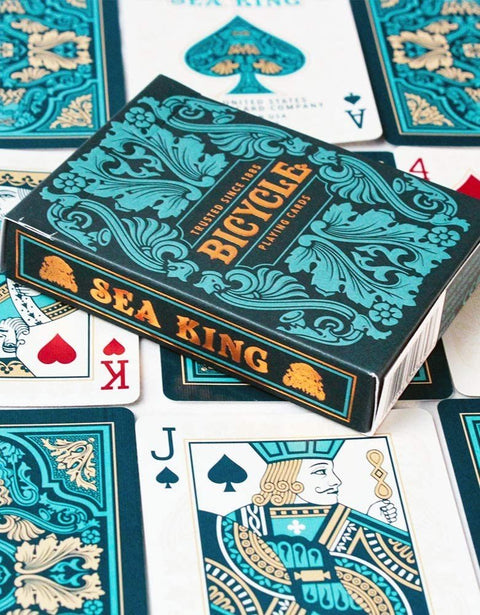 Bicycle Sea King kortos su turkio ir auksiniais ornamentais, dėžutė virš išskleistų kortų, matomas karalius ir valetas