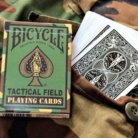 Bicycle Tactical Field žaidimo kortos žalia maskuotės dėžutė su juodomis nugarėlėmis, išskleistos ant kamufliažo