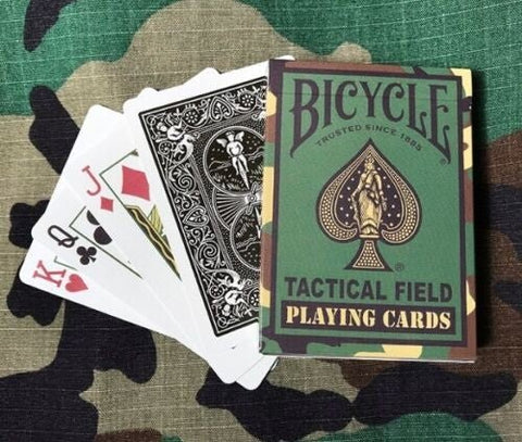Bicycle Tactical Field žaidimo kortos žaliame kamufliažo dėkle su išskleistomis kortomis ant kamufliažinio fono