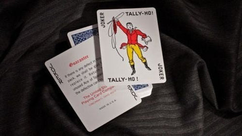 Tally-Ho kortos standartinio dydžio su atverstu juokdario korta ir mėlynu nugarėlių raštu ant tamsaus fono
