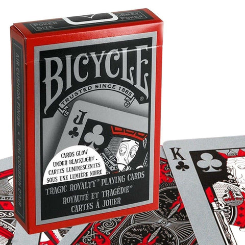 Bicycle kortos Tragic Royalty raudoname dėkle, matomas priekinis dizainas ir išskleistos juodai‑raudonos kortos su lipduku apie švytėjimą juodoje šviesoje