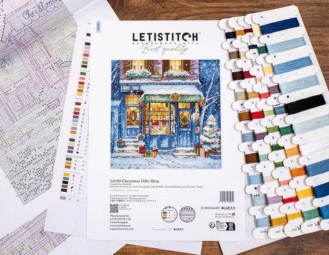 Kryželių rinkinys LETISTITCH „Christmas Gifts“ su žiemos parduotuvės motyvu, spalvotais siūlais ir schema, fotografuotas iš viršaus