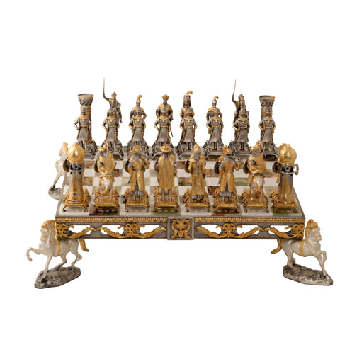 Šachmatai auksuoto ir sidabrinio metalo figūromis ant pakylėtos dekoratyvios lentos, matomi iš priekinio plano