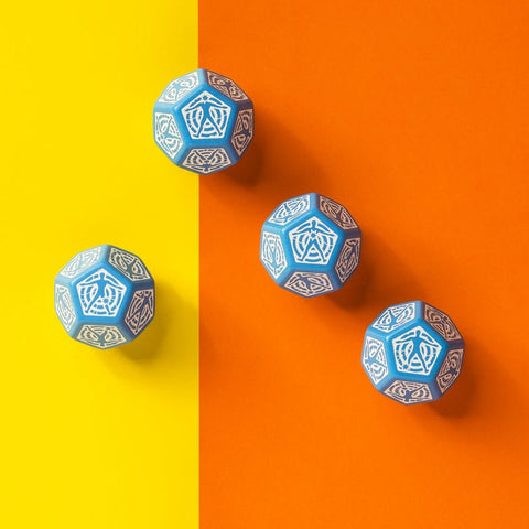 d20 kauliukai šviesiai mėlyni su baltu ornamentu, keturi išdėstyti diagonaliai ant geltono–oranžinio fono, matomas šešėlis