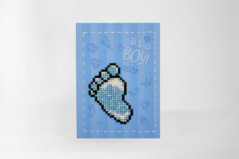Atvirukas It's a Boy! mėlynas, priekinė pusė su blizgančia mozaikine kūdikio pėda, mėlynais ornamentais ir balto siūlės rėmeliu