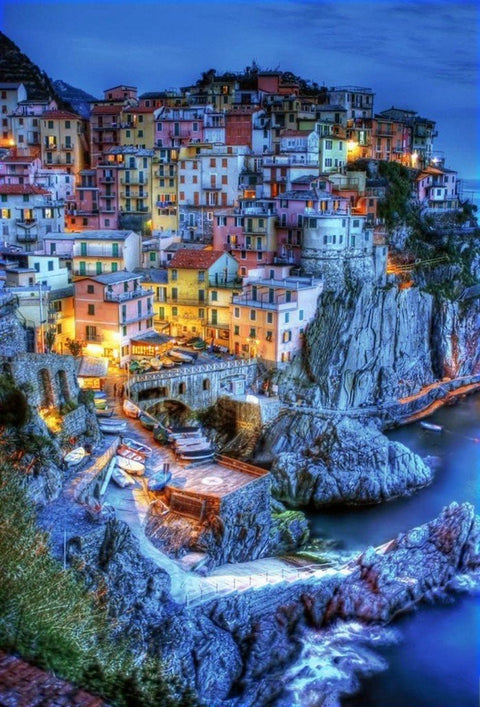 Sieninis plakatas Cinque Terre uolų kaimas vakare su šiltai apšviestais namais, uosteliu ir valtimis