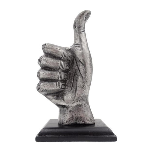 Statuetė sidabrinė nykščiu aukštyn ant juodo pjedestalo, grubios metalinės tekstūros, dekoratyvus stalo akcentas.