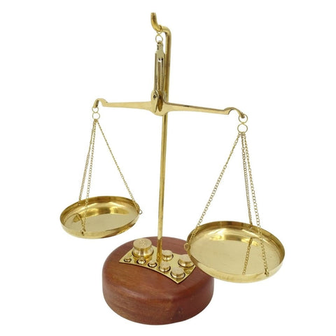 Svarstyklės ant apvalaus medinio pagrindo, žalvarinės lėkštės su sveriamaisiais svoriais, trijų ketvirčių kampu