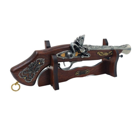 Senovinis pistoletas kopija ant tamsaus medinio stovelio su sidabrinėmis ir auksinėmis dekoracijomis, skirtas ekspozicijai