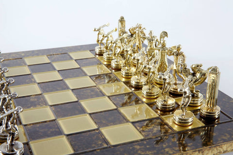Šachmatų rinkinys su auksinėmis ir sidabrinėmis figūrėlėmis ant tamsios marmurinės lentos, kampu priartinta auksinės pusės kompozicija