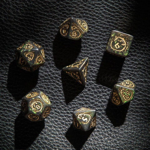 Metaliniai RPG kauliukai, 7 v., ant juodo odos fono su auksiniais raižiniais ir žalsvu patinu, žvilgsnis iš viršaus