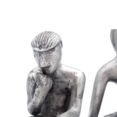 Statuetė sidabro tonu mąstančio vyro poza, mažo dydžio metalinė dekoro detalė, arti kairės figūros lankstinys ir tekstūra matoma