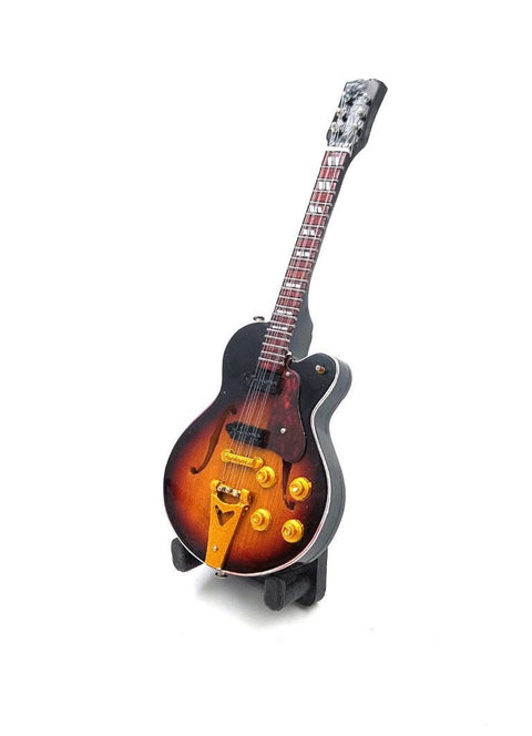 Gitara saulėlydžio apdaila, pusiau atvira elektrinė ant stovelio, matoma iš trijų ketvirčių kampo su auksiniais potenciometrais ir tiltu
