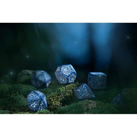 RPG kauliukai mėlyni metaliniai daugiasieniai kauliukai ant samanoto pagrindo, detaliai raižyti skaičiai ir ornamentai, rodomas komplektas