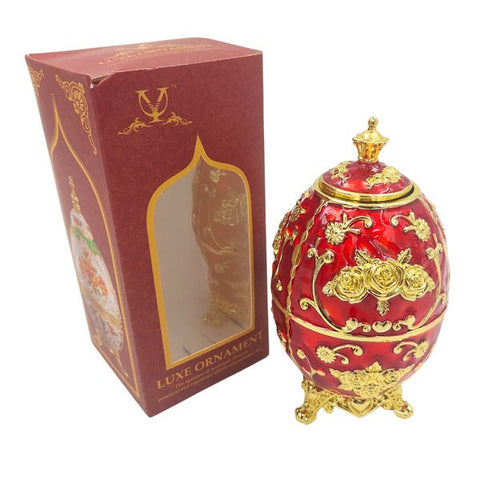 dekoratyvinis raudonas auksuotas kiaušinis‑dėžutė ant stovo su gėlių ornamentais, rodantis ir dėžutės pakuotę