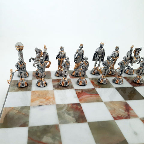 Šachmatai su sidabro ir auksu dengtomis viduramžių figūrėlėmis, arti nufotografuoti prie onikso šachmatų lentos