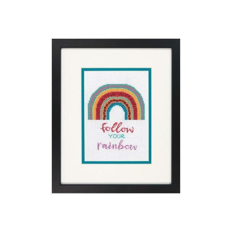 Siuvinys įrėmintas juodame rėme su turkio paspartu, spalvota siuvinėta vaivorykšte virš angliško užrašo "follow your rainbow"