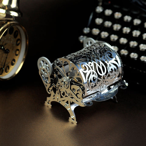 Muzikinė dėžutė sidabro metalinė, filigraniniai ornamentai ir atvira ritė su matoma mechanika artimame kadre
