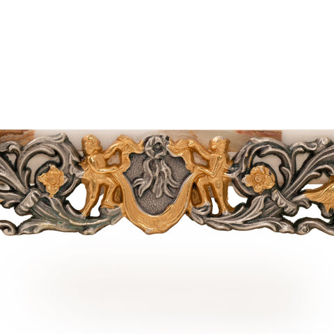 ornamentinė apdaila iš žalvario su auksuotu cherubų motyvu ir sidabro lapų raižiniais, artimas detalės kadras