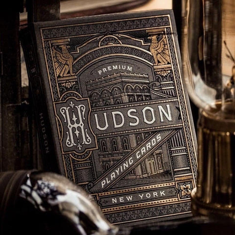 Kortų kaladė Hudson juodoje su auksiniais ornamentais dėžutėje, arti kampinis kadras su detalizuotu Niujorko pastato piešiniu