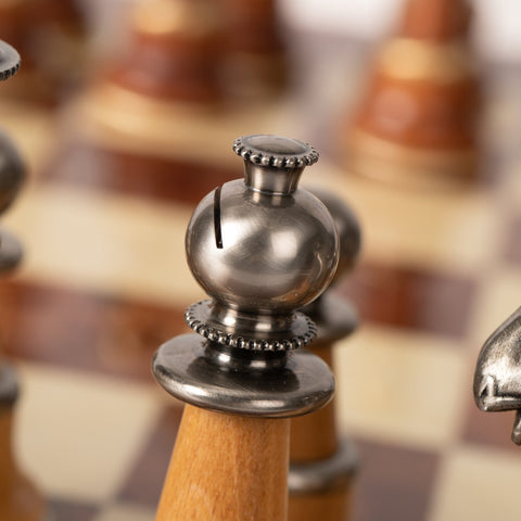 Šachmatų pėstininkas su poliruota antikinio sidabro metaline galvute ir šviesiu mediniu korpusu, artimas detalės kadras