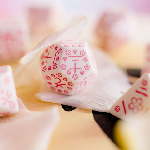 Mahjong plytelės baltos su rožiniais vyšnių žiedų raštais, arti užfiksuotos ant švelnaus šilko fono