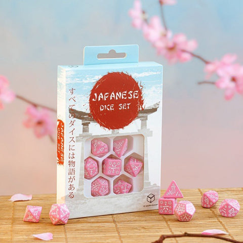 Kauliukų rinkinys – rožiniai japonų simboliais pažymėti septyni RPG kauliukai langinėje pakuotėje ant bambukinės lentelės, sakura fone