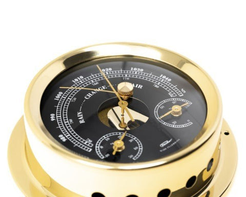 Barometras aukso apdaila su juodu ciferblatu ir trimis auksinėmis rodyklėmis, arti fotografuotas kampas, jūrinio stiliaus detalė