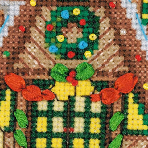kryželiu siuvinėtas kalėdinis ornamentas, ruda ir geltona su žaliais siūlais bei raudonomis karoliukų akutėmis, detalus arti nufotografuotas fragmentas