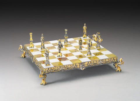 Šachmatai prabangus auksiniu ir sidabriniu apdaila ant pakylėtos gintaro ir balto marmuro lentos, perspektyva