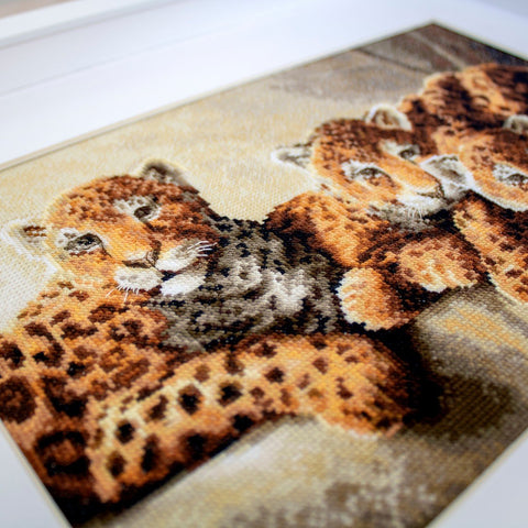Kryželių rinkinys su leopardų jaunikliais, arti mėlynas kampinis priartinimas parodo siūlų tekstūrą ir rėmo detalę