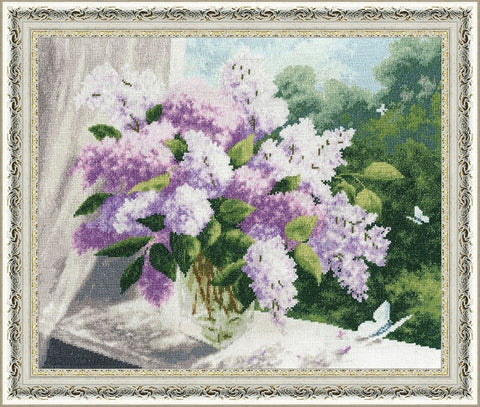 Siuvinėtas paveikslas: violetinių alyvų puokštė ant šviesaus fono, baltu ornamentuoto rėmo kampinis kadravimas