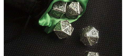 D20 kauliukai iš žalio aksominio maišelio — sidabro spalvos raižyti metaliniai žaidimo kauliukai ant juodo fono