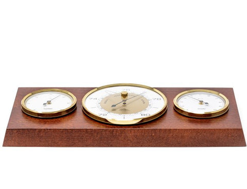 Meteorologinė stotis su auksuotais barometru, termometru ir higrometru ant tamsaus medinio pagrindo