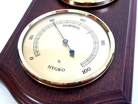 Higrometras ant tamsaus medinio pagrindo, aukso apvadais ir smėlio spalvos ciferblatu rodo apie 40 % drėgmę