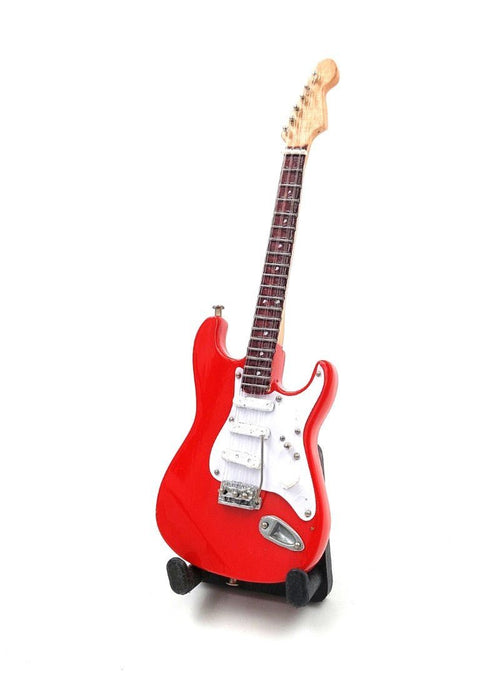 Elektrinė gitara raudona, pilno korpuso iš priekio ant stovo, blizgi apdaila ir balti pikapai