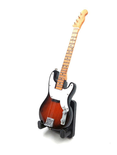 Elektrinė gitara rudai-raudonu sunburst paviršiumi, klevo kaklu ir baltu pickguardu, stovinti ant stovo priekinio kampo, akių lygyje