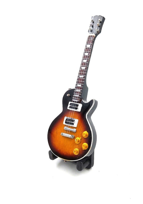 Elektrinė gitara sunburst apdaila su single‑cut korpusu, dviem pikapais ir keturiomis rankenėlėmis, stovinti ant stovo iš priekinio kampo